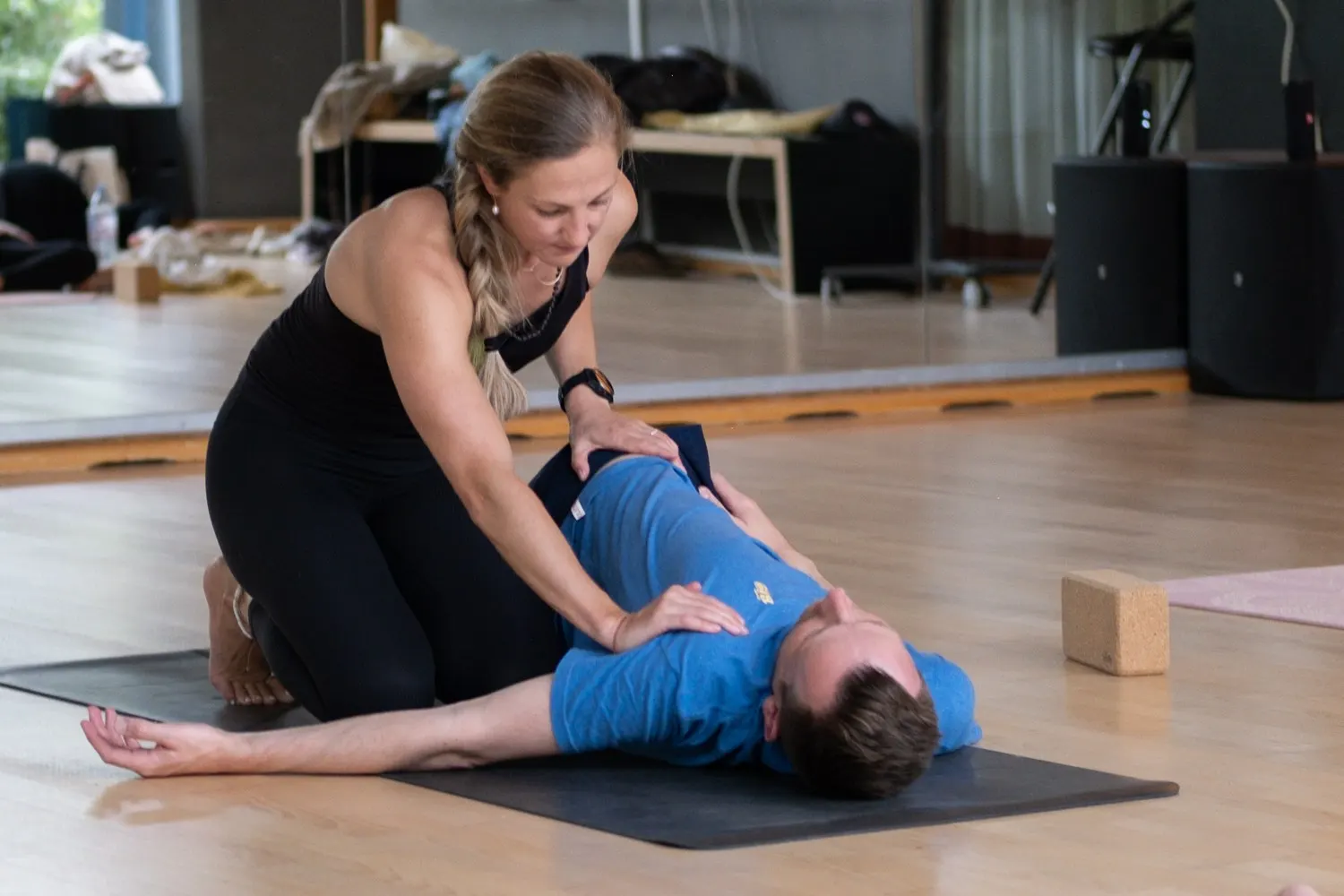 Leen begeleidt een deelnemer in een liggende draaihouding tijdens Yin yoga